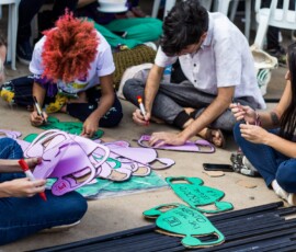 Foto: Mídia Ninja. Mulheres sentadas no chão com papéis que parecem úteros, onde diz útero livre.