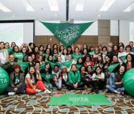 Representantes das organizações latinas e caribenhas posam em frente a um lenço verde grande.