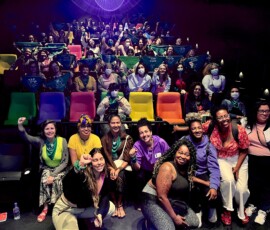 Público em uma sala de cinema. Vê-se bandeiras e lenços verdes espalhados.