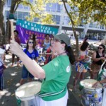 Batucada Unificada feminista no ensaio para a apresentação do Dia 28 de Setembro. Foto: Kati Tortorelli Diversas mulheres tocam instrumentos e batucada. Atrás há uma bandeira em roxo e verde.