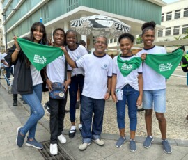Alguns jovens com uniforme escolar branco seguram lenços verdes em frente ao Museu de Arte do Rio.