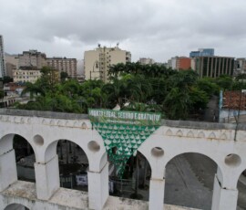 Vista aérea dos Arcos da Lapa, que amanheceram com a grande bandeira tecida com lenços verdes da Campanha Nem Presa Nem Morta. Foto: Kati Tortorelli. Vista aérea dos arcos da lapa, no Rio de janeiro. Há uma faixa verde que diz "Aborto legal, seguro e gratuito. Descriminaliza STF". Abaixo há uma bandeira formada por diversos lenços unidos pelas pontas, que formam um triângulo.