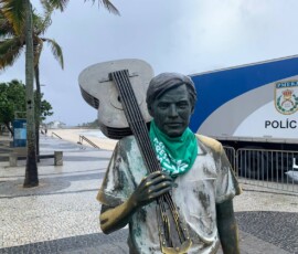 A estátua de Tom Jobim, no Arpoador, recebeu um adereço da luta pela legalização do aborto no amanhecer do dia 28 de Setembro. Foto: Amanda Gabriel. Foto da estátua de Tom Jobim vestindo lenço verde, no Arpoador.