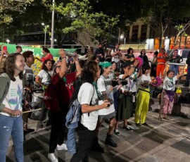 A Batucada Feminista, trajada com camisetas da Campanha Nem Presa Nem Morta, empolgou o ato no Dia de Luta pela Descriminalização do Aborto na América Latina e Caribe no Buraco do Lume, no Centro do Rio de Janeiro. Foto: Kati Tortorelli. Mulheres tocam instrumentos diversos organizadas em filas. Ao fundo há um lenço gigante da campanha nem presa nem morta.