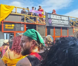 Foto de um carro de som com ativistas em cima no microfone e pessoas no chão.
