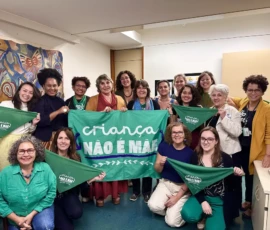 Mulheres posam pra foto com bandeiras e lenços da campanha Criança Não é Mãe. Ao centro, a deputada Erika Kokay (PT/ DF)