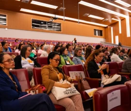 Foto da lateral do auditório com diversas mulheres sentadas.