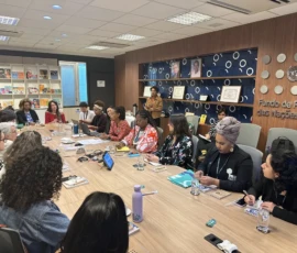 Foto de uma mesa grande de reunião, na sala do Fundo de Populações das Nações Unidas, na qual estão sentadas diversas integrantes da campanha Criança Não é Mãe e representantes institucionais do Fundo.