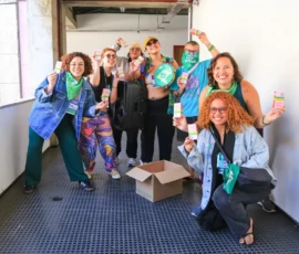 Foto de pessoas, num corredor, mostrando a caixa de remédio da ação Embaixo da Língua.