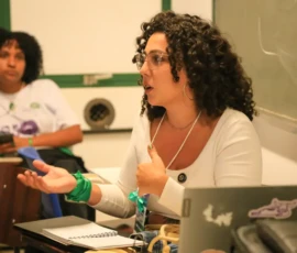 Foto em close de Laura Molinari, enquanto apresenta a oficina de "Comunicação para pesquisadoras sobre aborto" da Nem Presa Nem Morta.