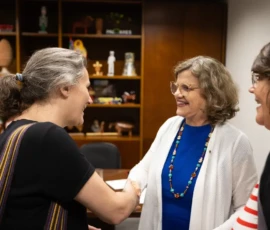 Foto da ativista Carla Angelini e a senadora Teresa Leitão PT/PE apertando as mãos no gabinete da parlamentar. Ao lado está Paula Viana.
