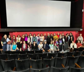 Pessoas posando para a foto em uma sala de cinema, posicionadas abaixo da tela.