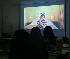 Foto de uma cena do filme "uma mulher comum" no telão com a sala escura.